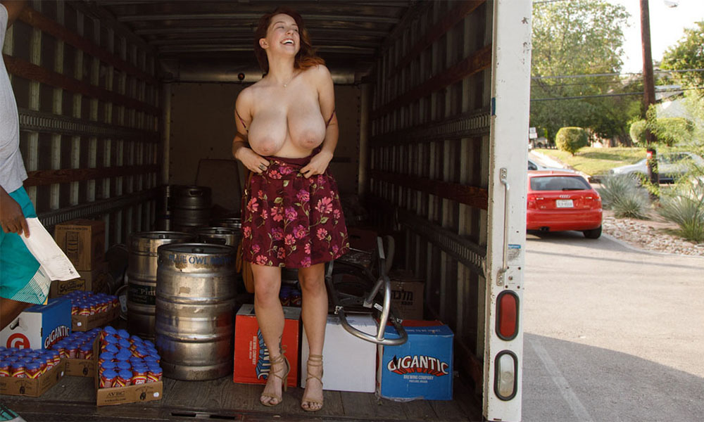 Large breasted redhead flashing her ample chest in the back of a delivery van